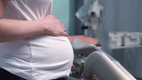 side view of pregnant woman's hands touching her belly in the medical consultation