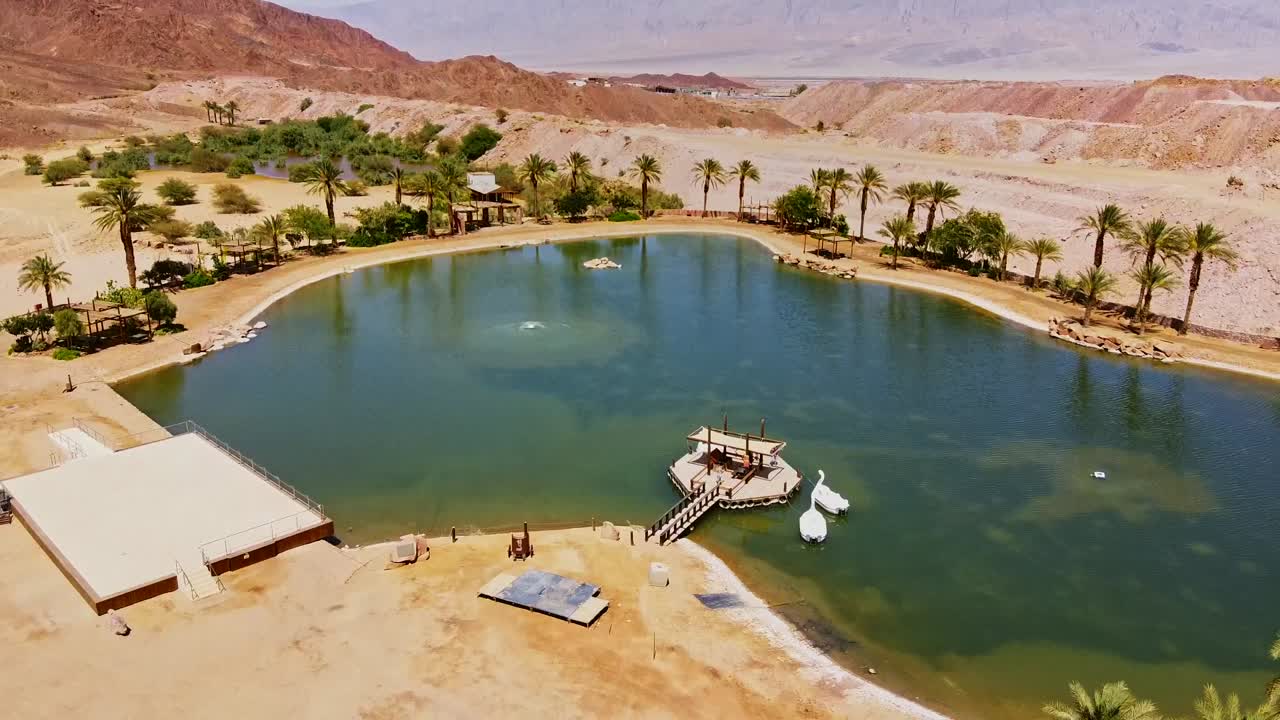 Aerial view of a stunning desert oasis, with turquoise waters contrasting golden sand dunes in Israel.