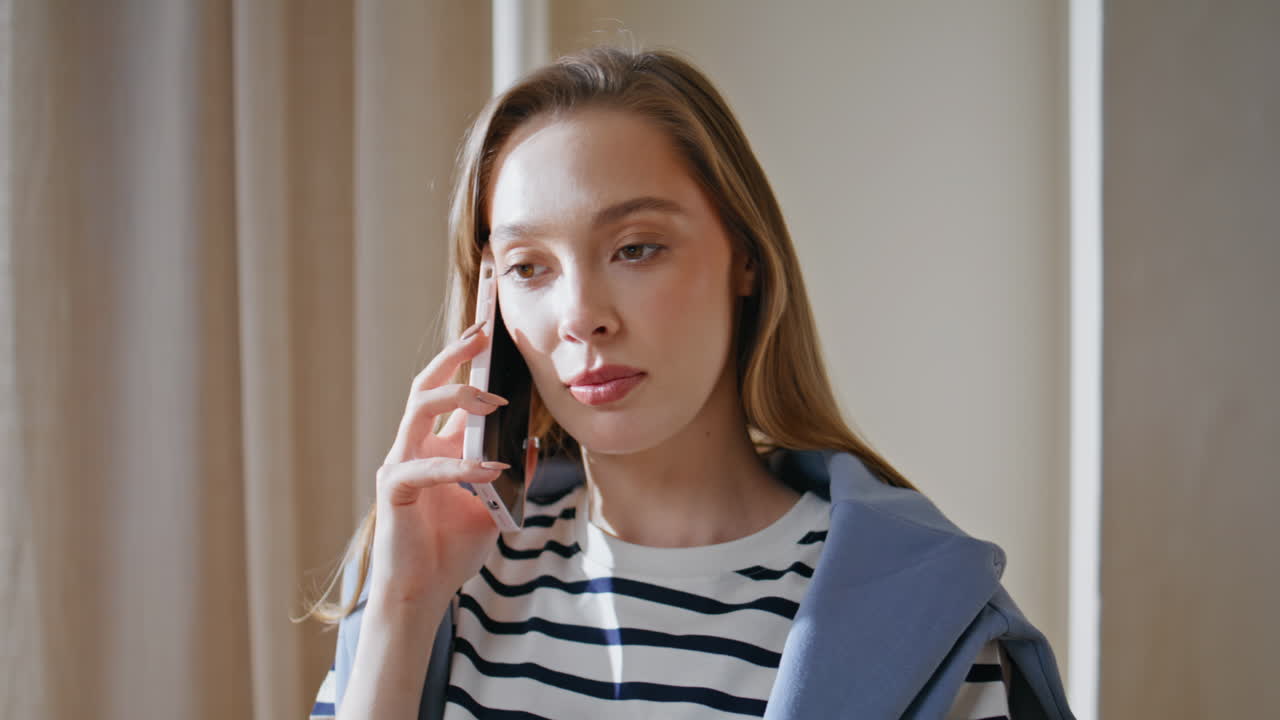 Calling girl discussing work by smartphone sitting light office interior closeup