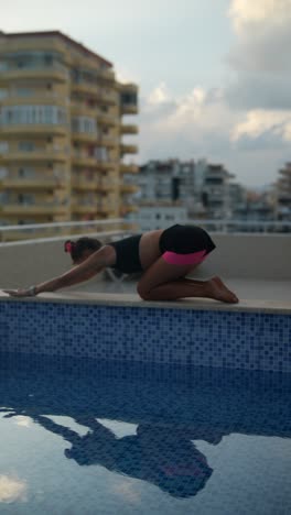 woman practicing yoga on rooftop by pool