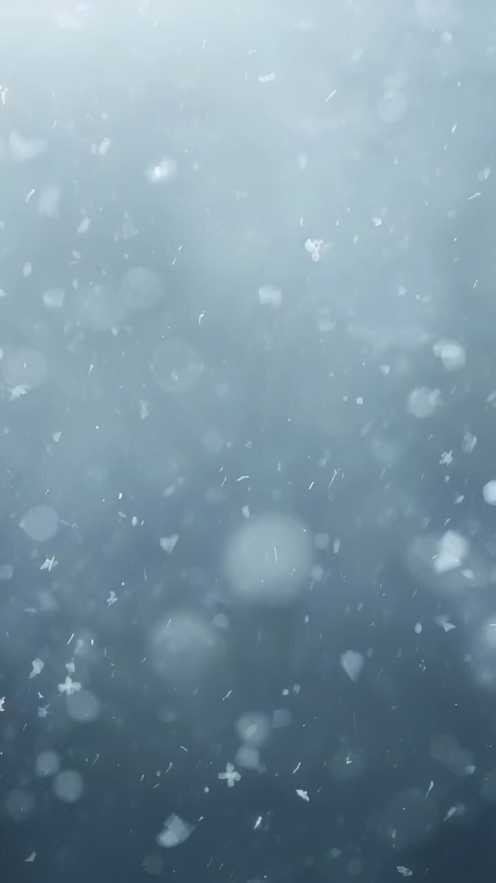 Vertical video: Drifting hexagon flake rotating while focus shifts in open sky, with falling flakes