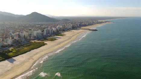 Aerial view of a long sandy Caiobá beach along the Brazilian Atlantic coast shoreline, Matinhos, Guaratuba, Paraná, Brazil