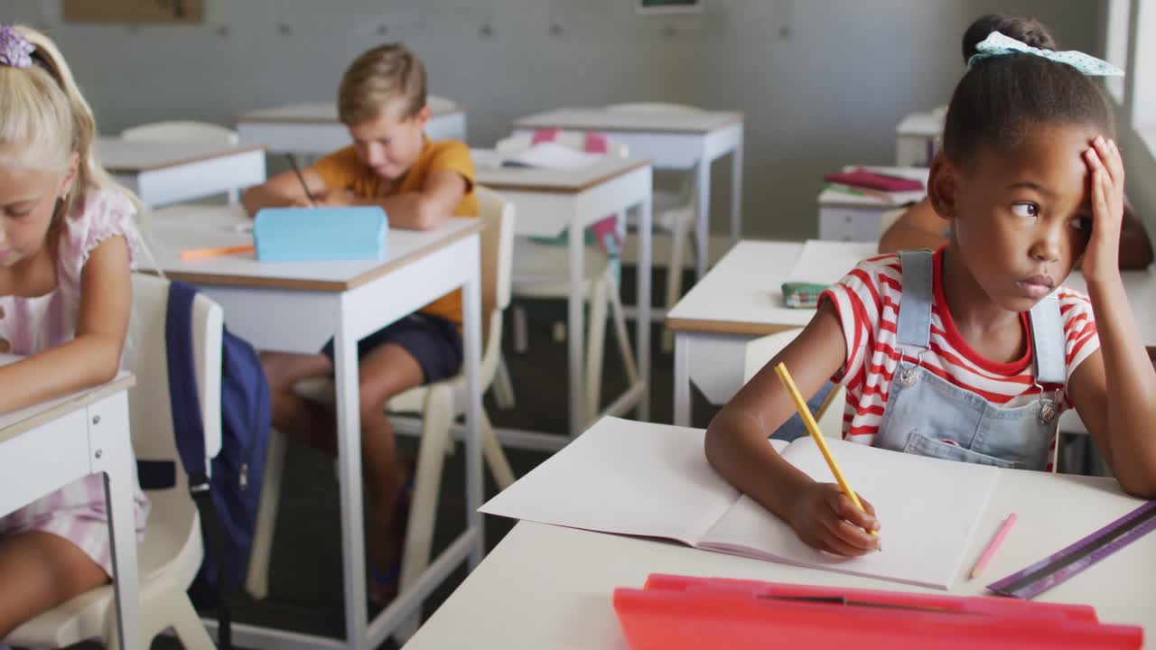 Video of thoughtful african american girl sitting at desk in classroom