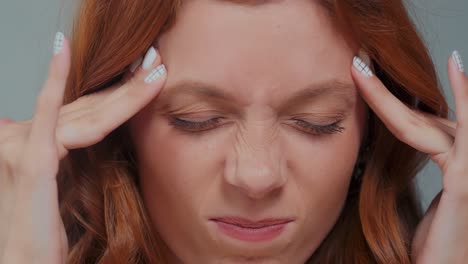 tired caucasian woman breathes deeply and massages temples to relax closeup