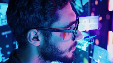 side profile of a man with glasses in a neon-lit room, viewed from a close-up angle