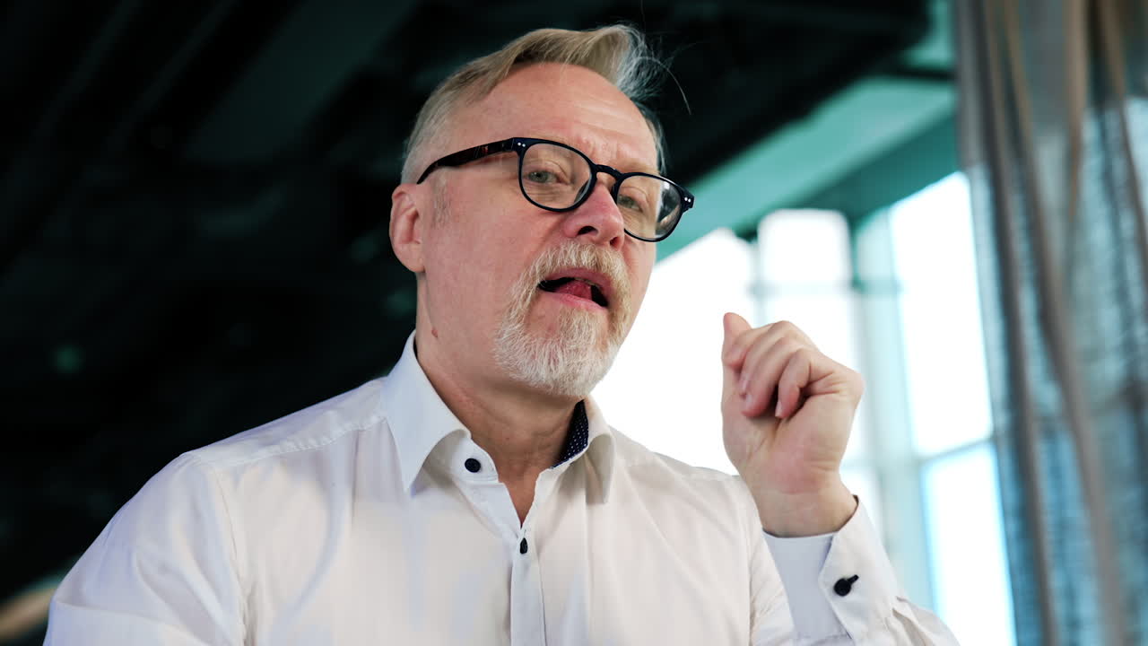 Man wearing glasses thinking over the idea. Pensive man looks at window and then turns to camera. Low angle view.