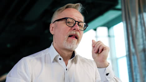 man wearing glasses thinking over the idea. pensive man looks at window and then turns to camera. low angle view.