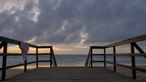 puesta de sol serena en la playa: pasarela de madera hacia el océano