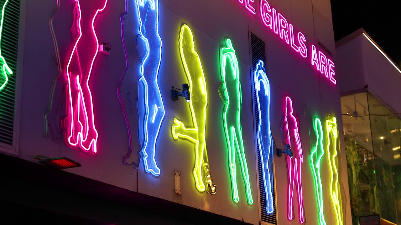 Neon silhouettes illuminate a lively street in Phuket, Thailand. Bright colors and dynamic lighting create an energetic nightlife atmosphere