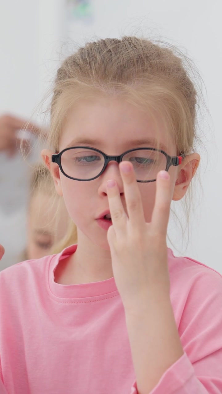 Bambina con gli occhiali che conta sulle dita