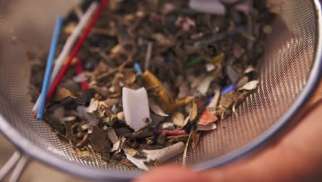 micro plastic in a sieve, a hand picking through the waste