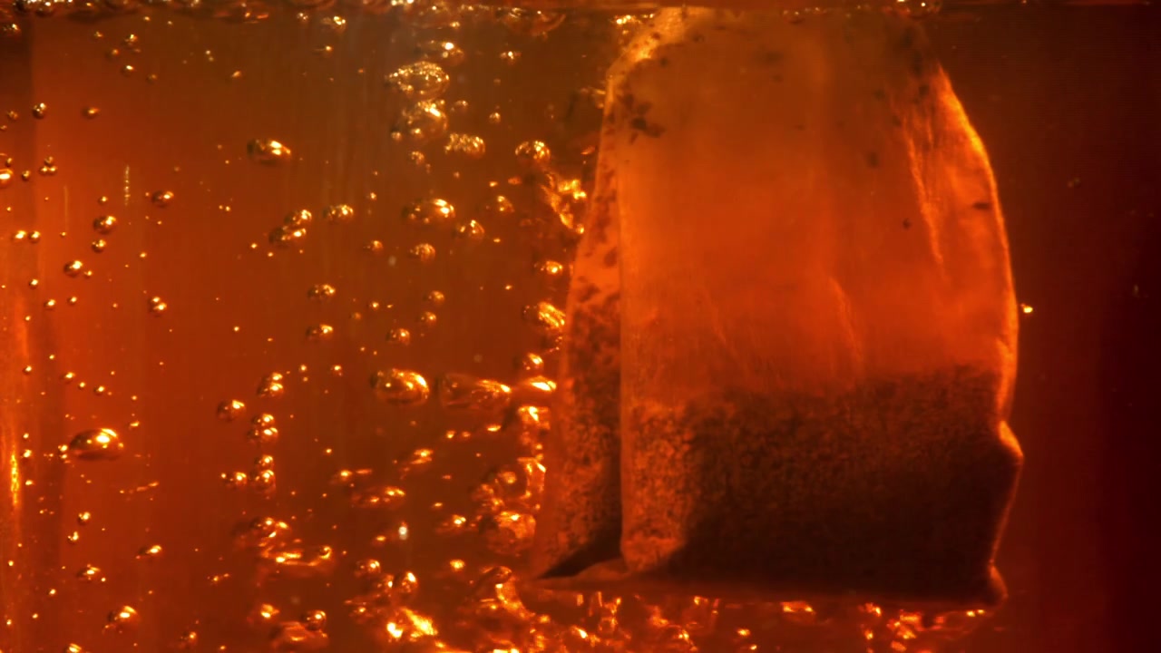 Close-up of Tea Bag Steeping in Hot Water with Bubbles