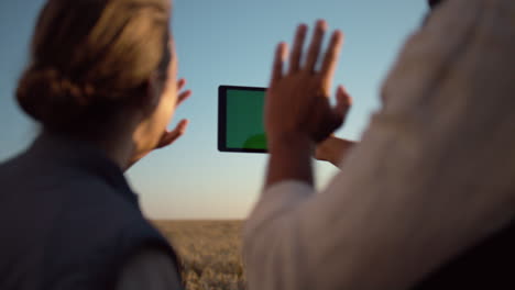 Couple-holding-chroma-key-pad-computer-at-cultivated-grain-harvest-sunlight.