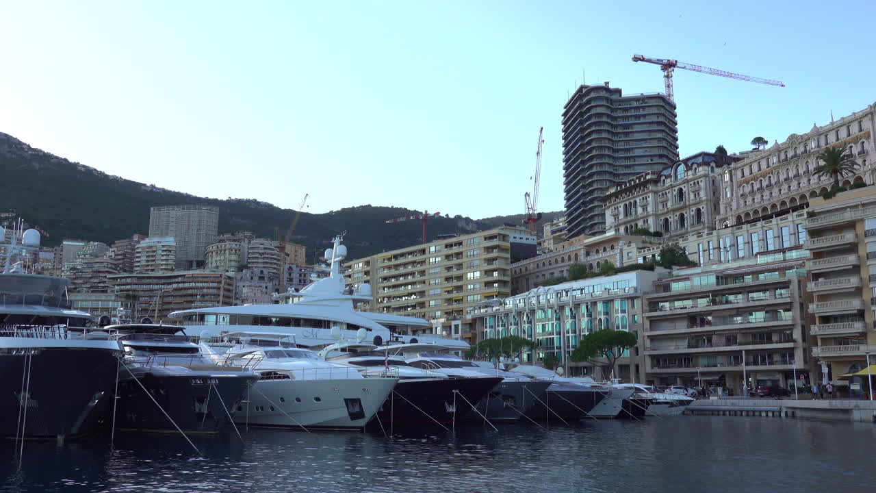 Monte Carlo, Monaco - 4 luglio 2025: Yacht e lance ormeggiati vicino al moderno Yacht Club a più livelli, con residenze di lusso lungo la banchina