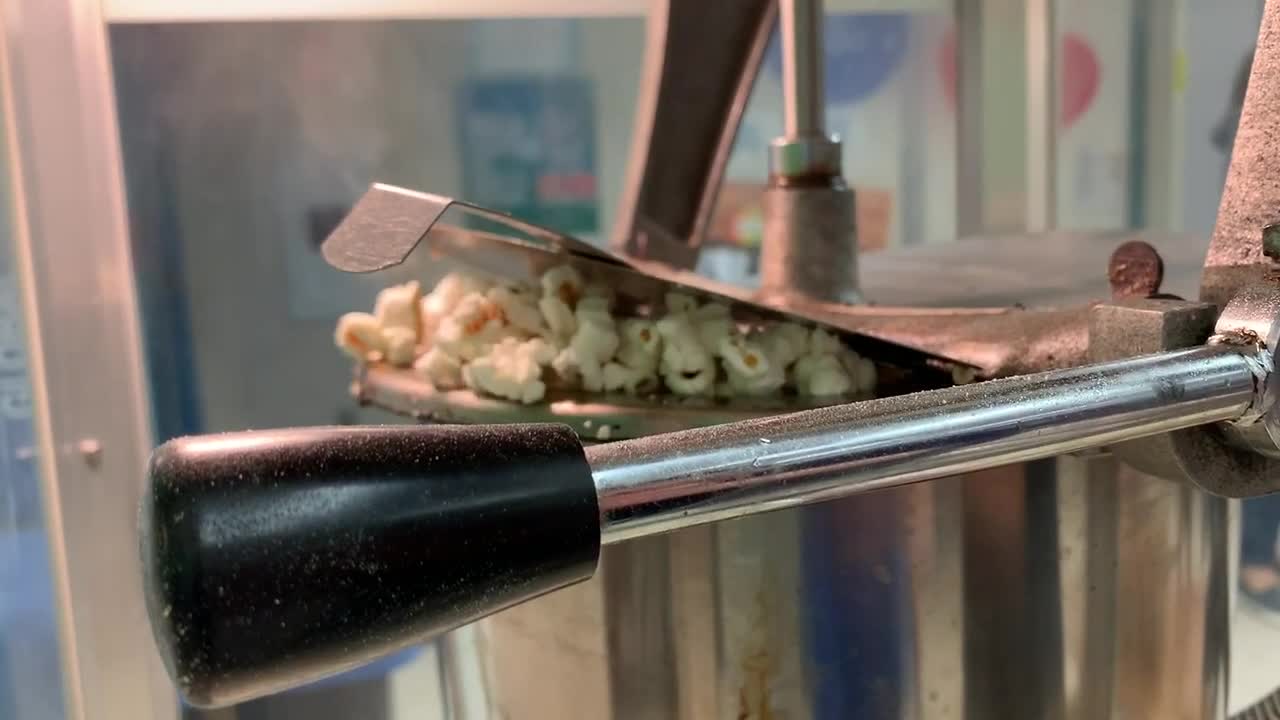Fresh popcorn popping out of a popcorn making machine used for fundraising events, carnivals, Movie Nights, and parties. HD stock footage