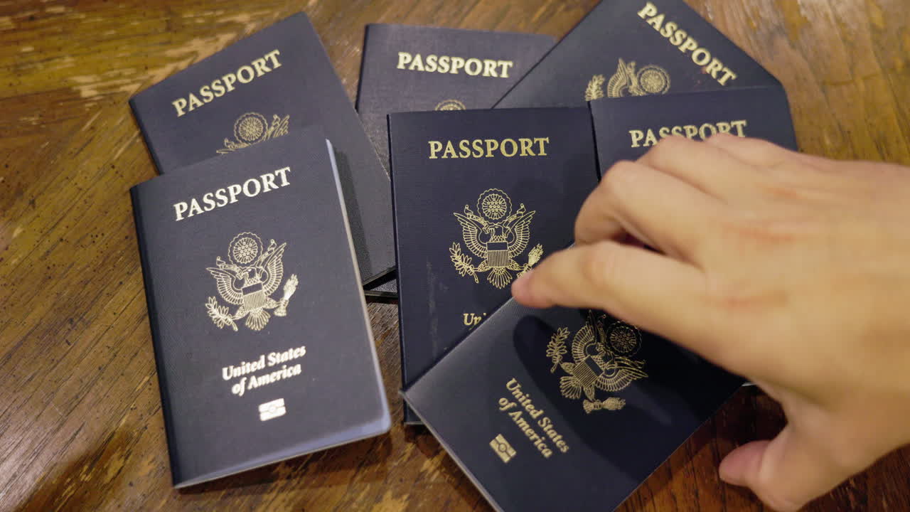 Manos recogiendo varios pasaportes estadounidenses de una mesa de madera