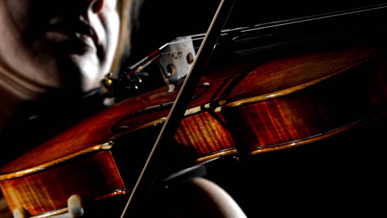 un primer plano extremo de una música femenina tocando el violín, sobre un fondo de estudio negro sin fisuras