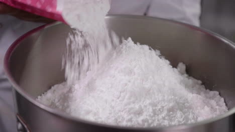 el azúcar glas se vierte en un tazón metálico grande para mezclar de cerca