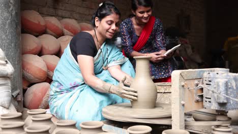 mother and daughter using digital tablet at pottery workshop