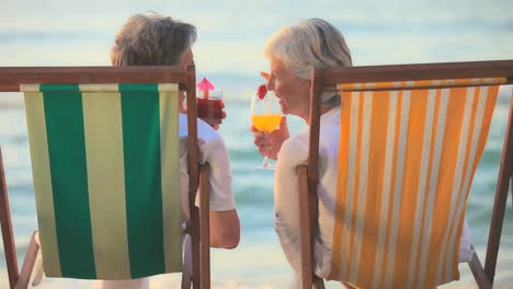 elderly couple drinking cocktails in front of the sea