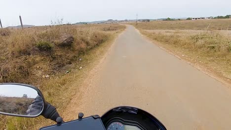 Motociclista-Montando-Bicicleta-En-Asfalto-Remoto-Durante-El-Día-Desde-Un-ángulo-Plano