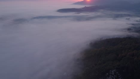 Sunrise-at-Sacco-valley-covered-in-low-hanging-clouds-mist,-aerial