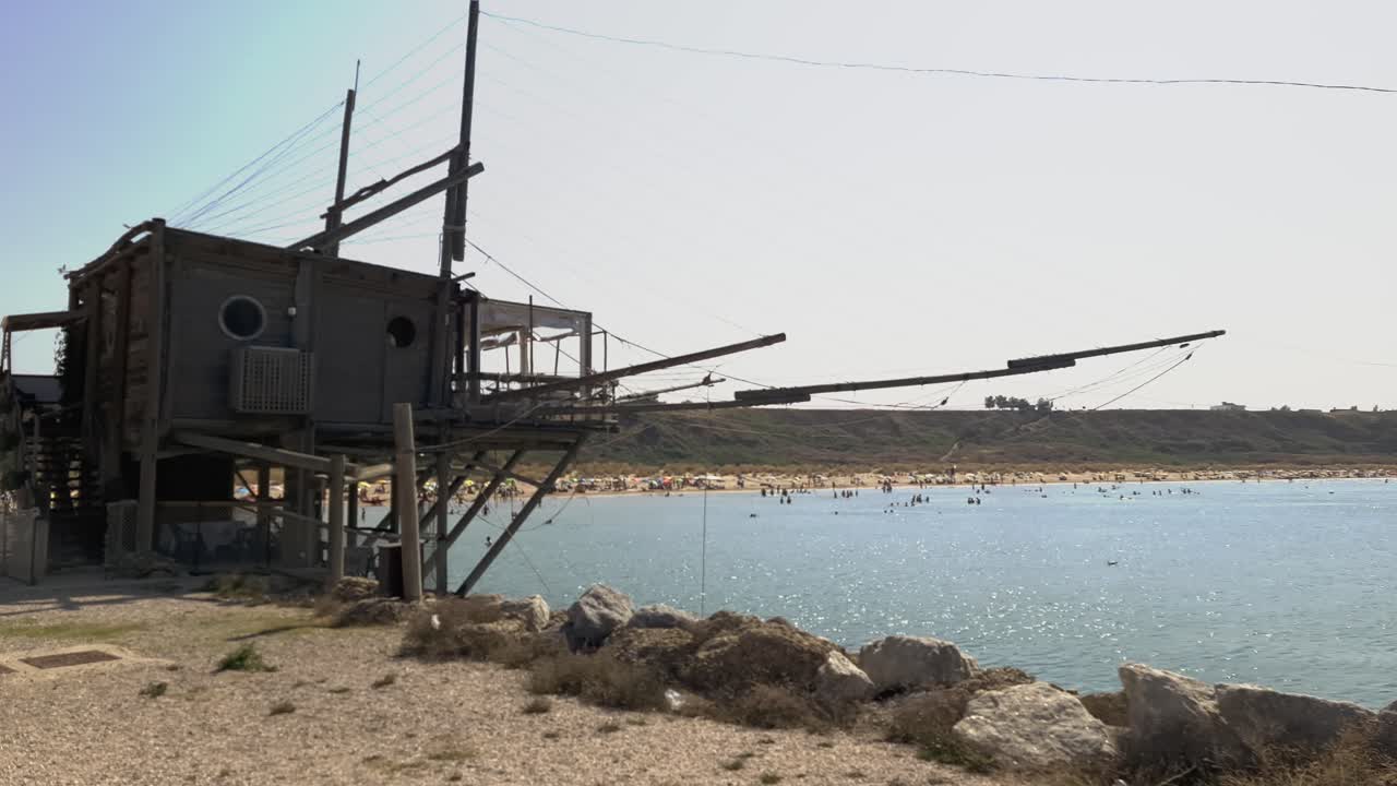 푼타 펜나 보호구역 해변의 트라부코 낚시 집에 있는 전통 레스토랑과 이탈리아 아브루초에서 목욕하는 사람들