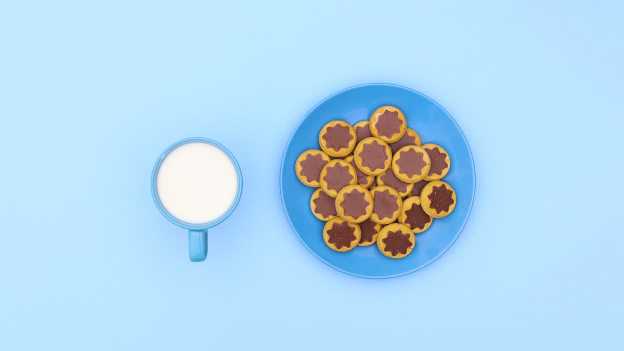 taza de leche y galletas en el plato azul girar en círculo en el tema azul. detener el movimiento
