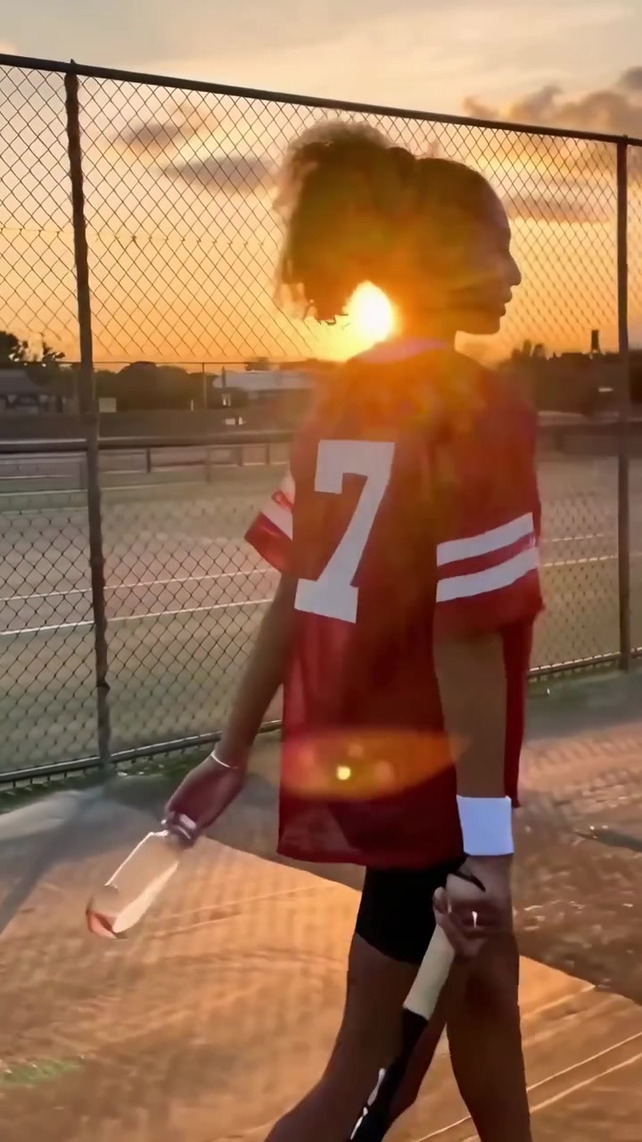 Jovem Mulher Caminhando em Quadra de Tênis ao Pôr do Sol