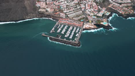 aerial establishing shot approaching coastal village and boat port in tenerife spain, 4k