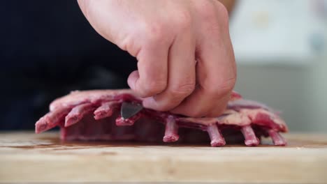 chef carefully trimming rack of lamb before cooking