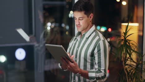 man working on tablet by window at night
