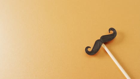 video of false moustache on stick on yellow background with copy space