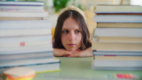 retrato de un joven estudiante, cansado de la cantidad de estudio, empujando una pila de libros