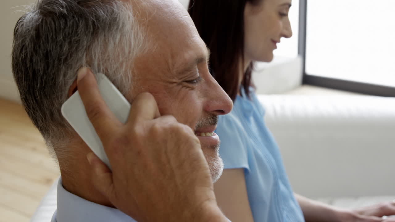 pareja linda sentada en el sofá usando un dispositivo de alto