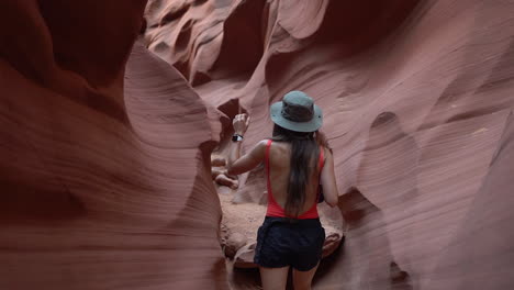 Back-of-young-woman-with-photo-camera-walking-in-a-narrow-slot-sandstone-canyon,-amazing-landscape-and-natural-beauty-of-Antelope-Canyon,-Arizona-USA,-slow-motion