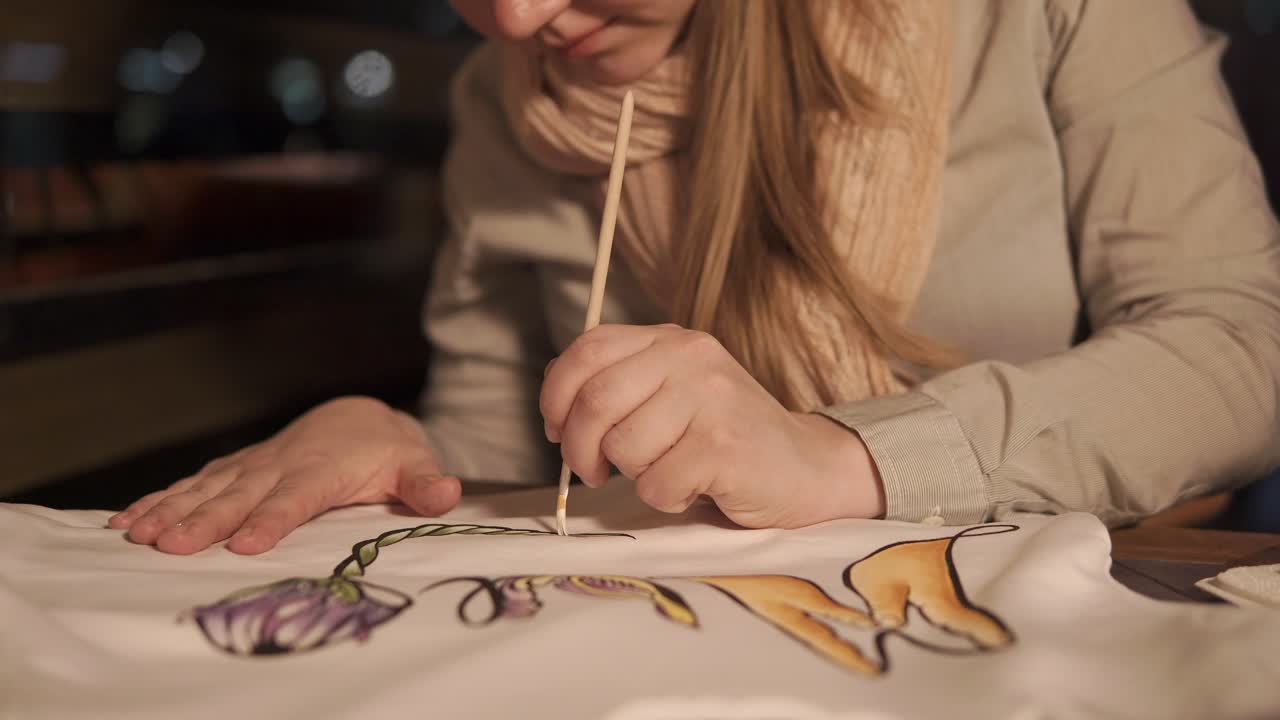 mujer pintando un diseño floral en una camiseta
