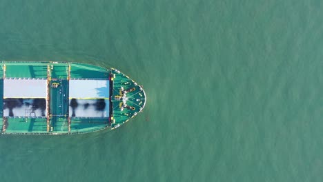 Aerial-top-down-shot-of-Large-Coal-Ship-moving-through-ocean-water,-Gladstone-Queensland-Australia