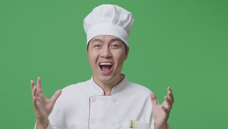 close up de hombre asiático chef sonriendo y diciendo wow mientras estaba de pie en la pantalla verde estudio de fondo