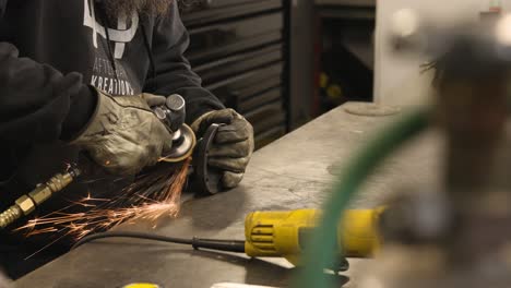 man in machine shop grinding a spindle hub with an angle grinder