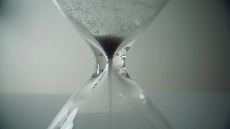 Black sand flowing hourglass standing table closeup. Last seconds of countdown