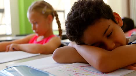 caucasian schoolboy sleeping at desk in classroom at school 4k