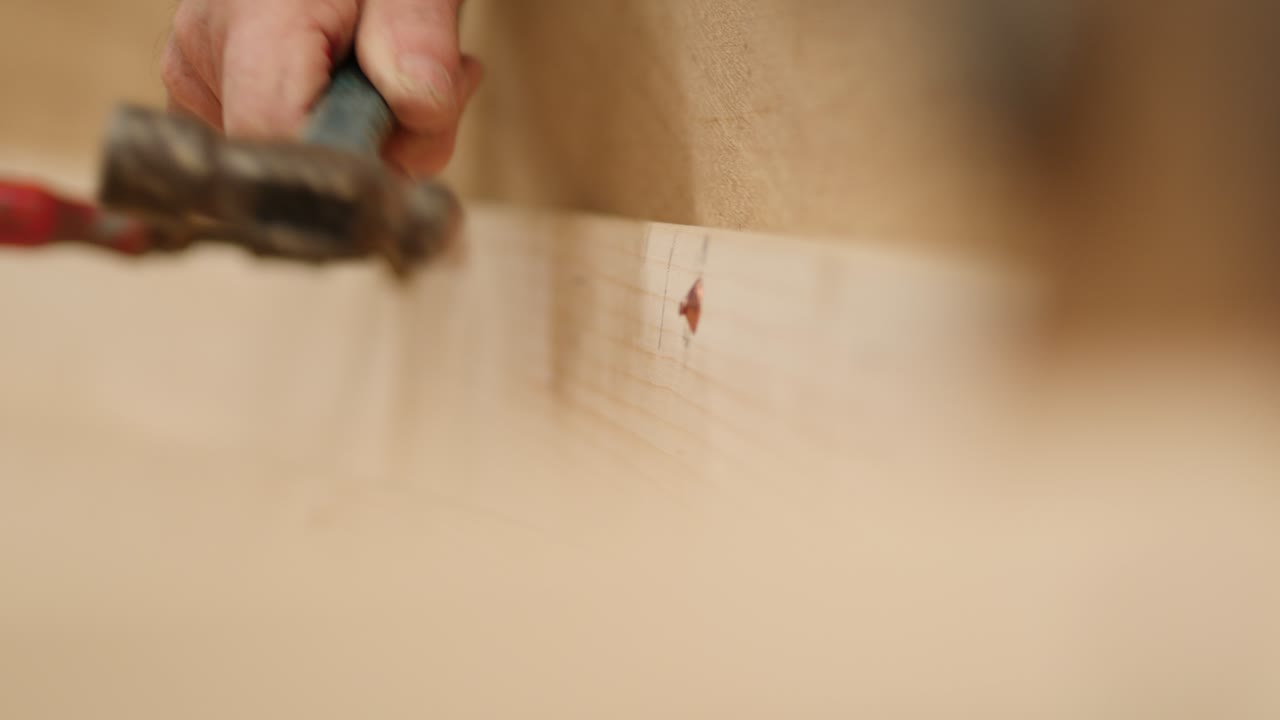 A shipwright hammers copper nail over rove boat building