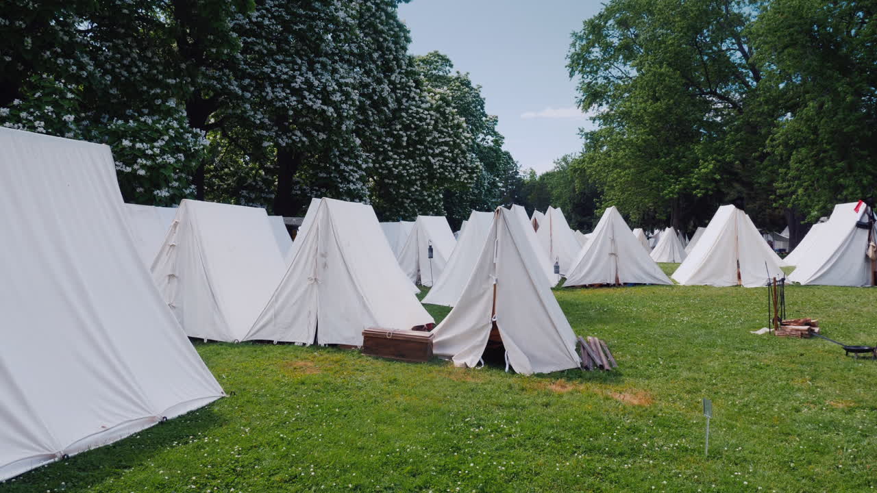 오래된 군사 캠프 텐트 행은 전쟁 시대의 숲 재건에 서 있습니다.