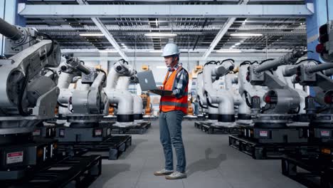 Engineer Working with Robotic Arms in a Factory