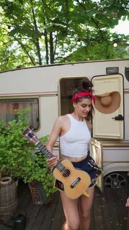 woman playing ukulele near a camper van