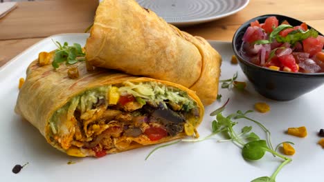 Tasty-chicken-wrap-with-vegetables,-cheese,-chili-flakes-and-salad-in-Marbella-Spain,-brunch-during-summer-at-a-restaurant,-4K-shot