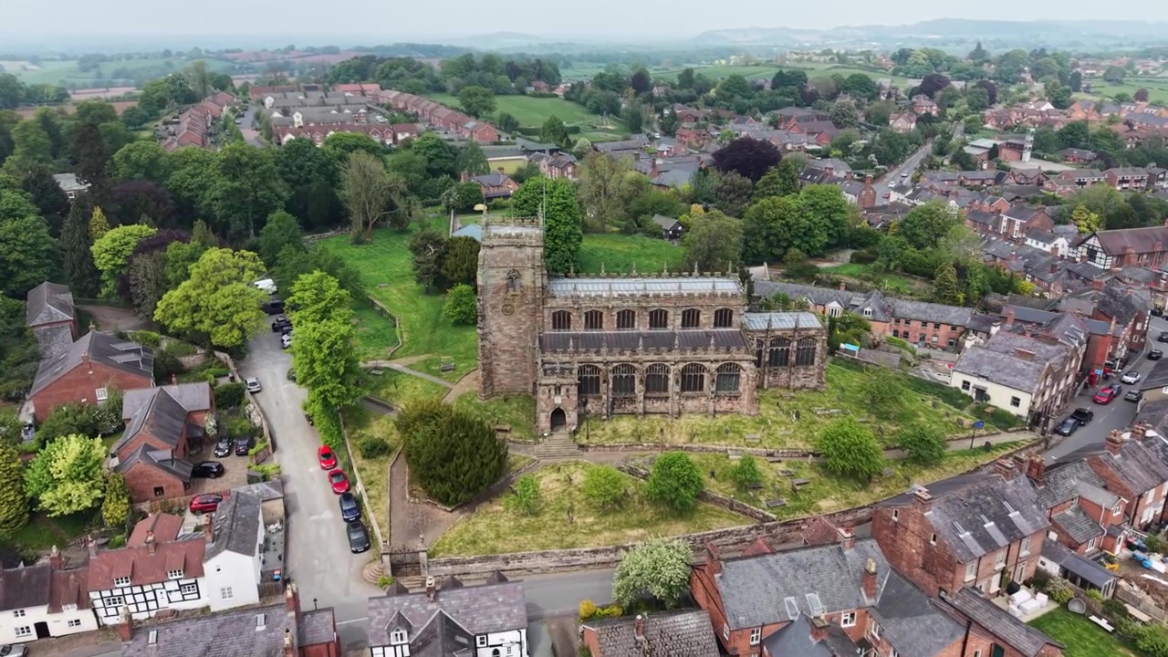 A deslumbrante Igreja de St Oswald e a vila circundante de Malpas - drone girando de longe e depois se aproximando, Cheshire, Reino Unido.