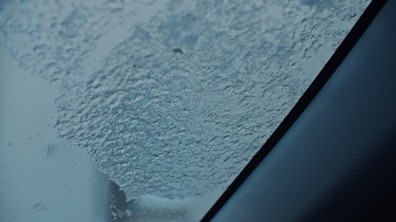 Cleaning a car windshield with an ice scraper, freezing rain over night covered the hole windshield