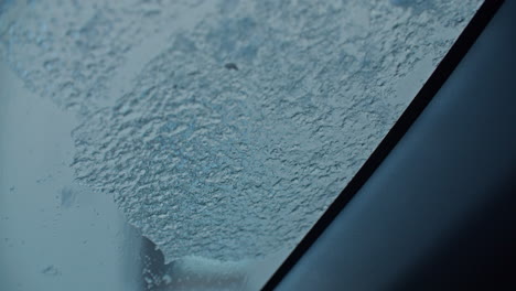 cleaning a car windshield with an ice scraper, freezing rain over night covered the hole windshield